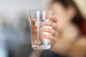 A woman holding a glass of water.