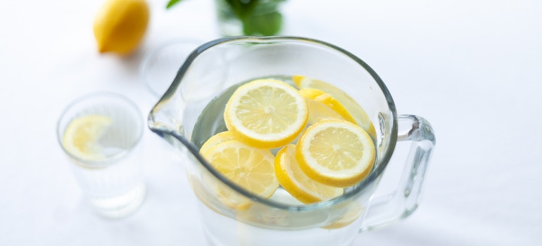 a jug of lemon water with a glass and lemons