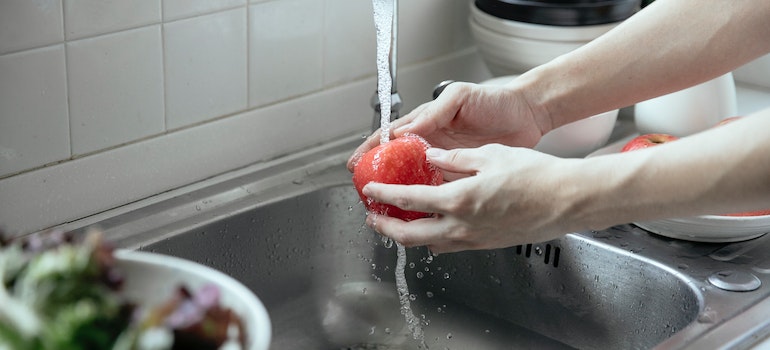 a person washing an apple and forming clean water habits