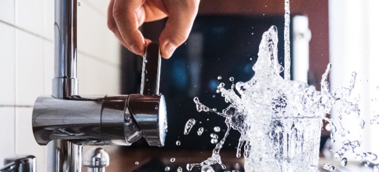 A person pouring water from the tap