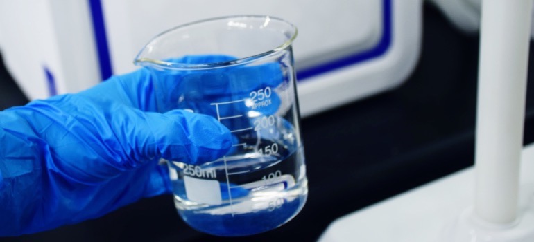 A person holding a beaker of water in a lab