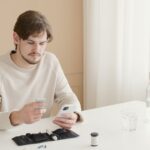 A man holding his phone and a white ceramic mug