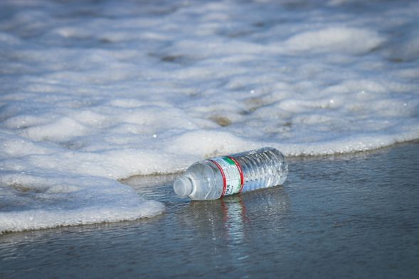 Plastic water bottle on seashore showing bottled water pollution