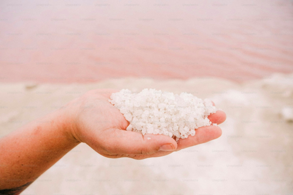 Hand holding a handful of sea salt illustrating potential microplastic contamination.