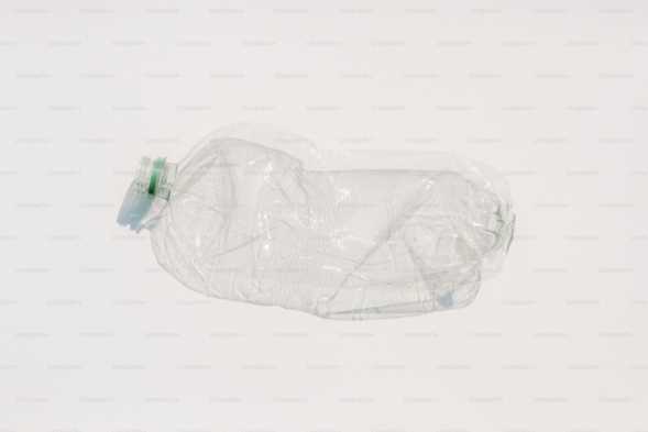 Crushed plastic water bottle on white background symbolizing plastic pollution and microplastic sources