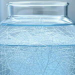 Glass jar with microplastic fibers floating in water inside a laboratory setting